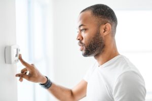 A man choosing the temperature on a thermostat